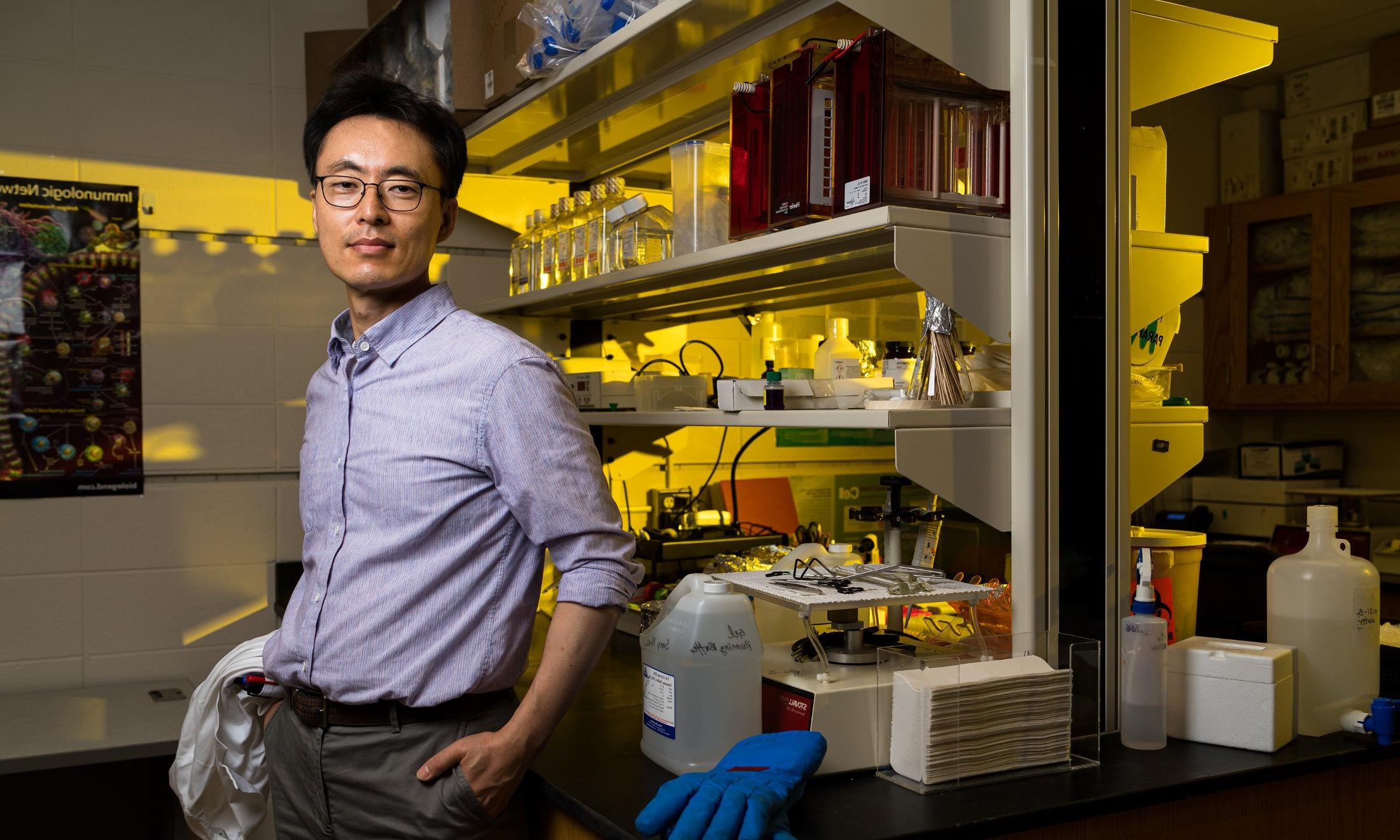 Dr. Sang Rhee with his back leaning against a counter in a lab